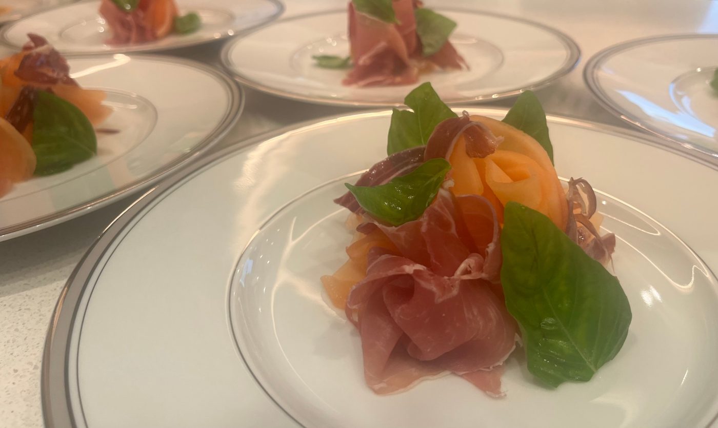Prosciutto and melon with fresh basil on platinum-rimmed china by chef Troy Davidson
