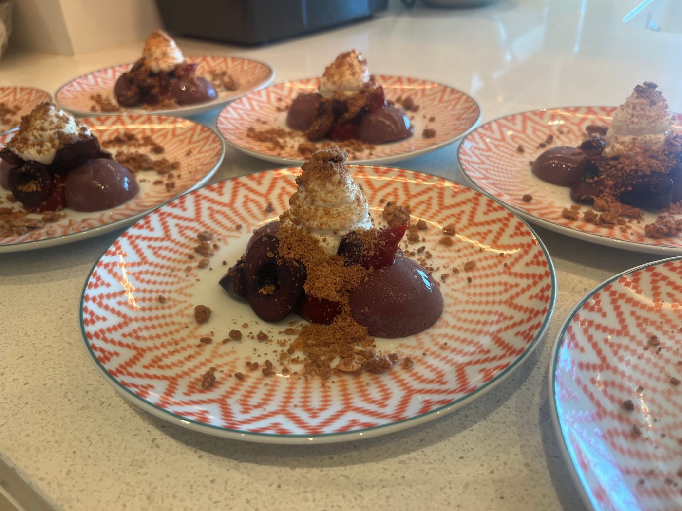 Cherry bavarois with fresh cherries, cream and crumble on patterned plates by chef Troy Davidson